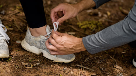 Hombre-Ayudando-A-Una-Mujer-Con-Los-Cordones-De-Los-Zapatos