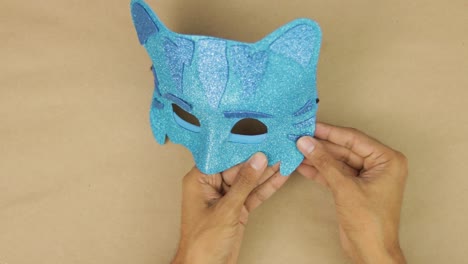 Hands-gluing-last-details,-blue-diamond-foam-Catboy-mask-from-PJ-Masks-for-carnival