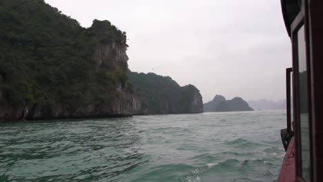 Tourist-boat-sailing-in-tropical-landscape-with-mountains,-view-from-inside-deck