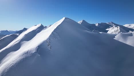 Un-Dron-Vuela-Alrededor-De-Una-Gran-Montaña-Cubierta-De-Nieve-En-Los-Alpes