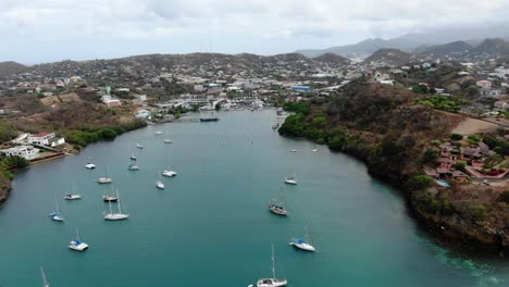 Sailboats-in-prickly-bay-marina,-grenada,-with-tropical-coastline,-aerial-view