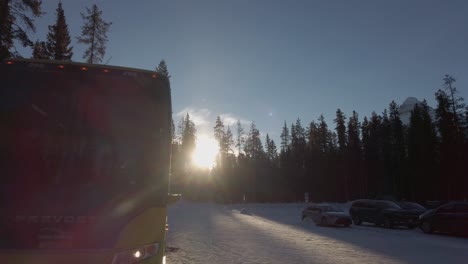 Passenger-bus-on-snowy-parking-lot-sun-backlit-reveal