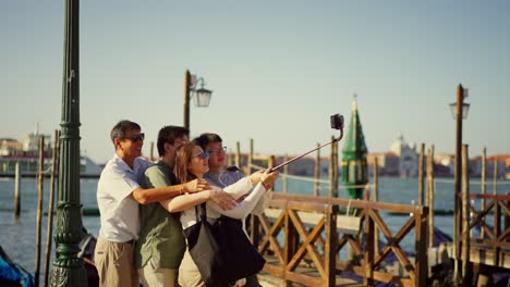 Family-of-tourists-from-Asia-takes-selfie-with-a-selfie-stick-in-the-famous-San-Marco-Square,-Venice