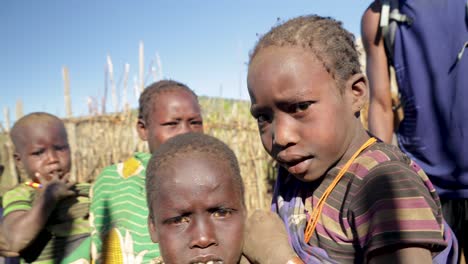 Toma-En-Cámara-Lenta-De-Niños-Tribales-De-Uganda-Mirando-A-La-Cámara-Mientras-Se-Encuentran-En-Su-Remota-Aldea