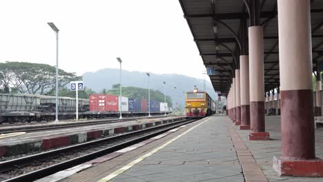 Low-angle-view-of-a-local-passenger-train-slowing-down-the-speed-while-arriving-at-Thungsong-Junction-Railway-Station,-the-junction-for-the-Southern-mainline-and-Kantang-Line-to-Trang-Province