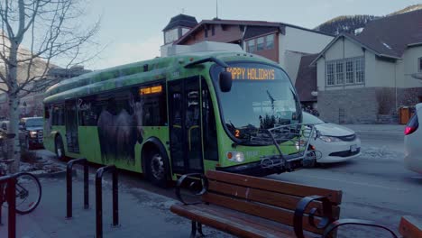 Electric-Bus-in-service-on-street-parked-at-evening-in-downtown-Banff,-Alberta,-Canada-pull-out