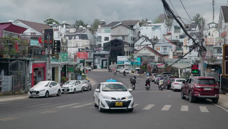 Urban-Da-Lat-City-Street-Traffic-with-Many-Commuters-Riding-Motorbikes-and-French-Style-Building-Facades-on-Cloudy-Day