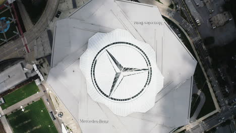 Rotierende-Vogelperspektive-Eines-Großen-Dreizackigen-Sterns-Als-Mercedes-Benz-Logo-Auf-Dem-Dach-Eines-Modernen-Mehrzweckstadions