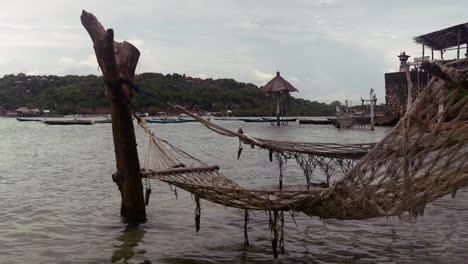 Rope-Mesh-Hammock-Suspended-On-Water-By-The-Beach,-Tourism-In-Indonesia