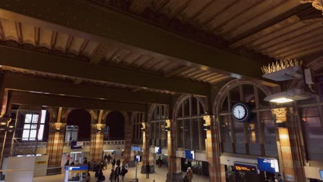 El-Vestíbulo-Principal-De-La-Estación-Central-De-Ámsterdam-Se-Inclina-Hacia-Abajo-Sobre-Los-Carteles-De-La-Multitud-Y-El-Reloj,-Con-Una-Toma-Panorámica-Total