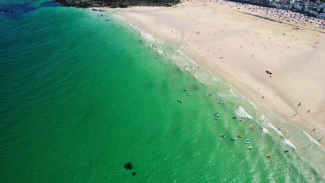 Aerial-Drone-Shot-Over-St-Ives-in-Cornwall-with-People-Swimming-at-Porthmeor-Beach