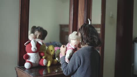 Rear-view-of-a-young-girl-playing-with-teddies-at-her-free-time-with-her-reflection-on-mirror