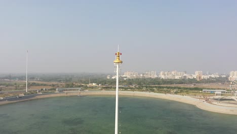 rajkot-atal-lake-drone-view-drone-camera-showing-big-road-behind-it-and-lots-of-ashok-chakra-around,-Rajkot-New-Race-Course,-Atal-Sarovar