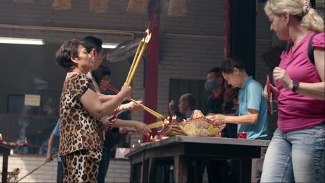 Gente-Encendiendo-Velas-En-Oración-En-La-Pagoda-Del-Emperador-De-Jade,-Saigón,-Vietnam,-Transmitiendo-Espiritualidad-Y-Tradición.