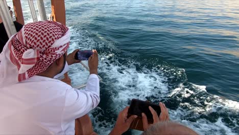 Omani-wearing-loincloths,-local-dress,-traveling-by-boats-in-the-Arabian-Sea,-Musandam,-Sultanate-of-Oman,-Delfin-watching