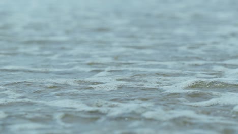 Close-up-of-ocean-waves-crashing-on-the-beach-with-beautiful-white-sand-background