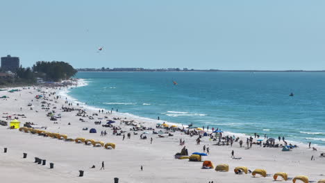 Beautiful-Aerial-Vista-of-Treasure-Island-Beach-looking-out-at-waves-with-beachgoers-flying-kites-and-walking