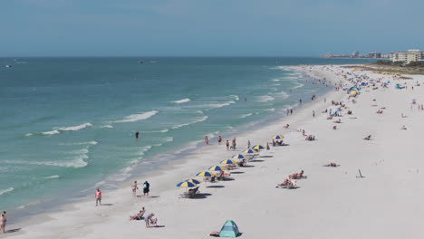 Aerial-shot-flying-over-Treasure-Island-Beach-tourists-walking-on-shore-with-waves