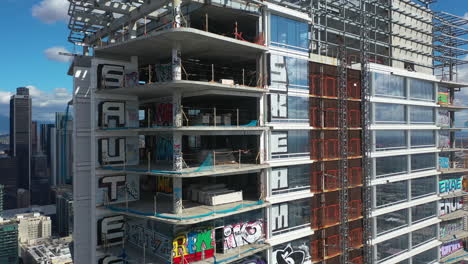 Aerial-descending-shot-in-front-of-a-abandoned-high-rise-covered-in-Graffiti,-in-LA