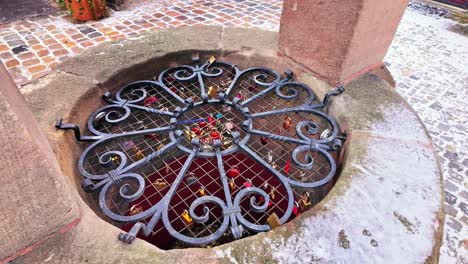 Locks-of-love-on-the-metal-grate-of-a-large-well-in-the-Handwerkerhof-in-Nuremberg,-Germany