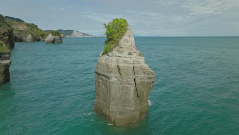 Natural-limestone-sea-stack-column-near-shore-of-New-Zealand,-aerial