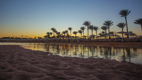 Sunset-Time-Lapse-Behind-Palm-Trees-and-Umbrellas-at-Pickalbatros-Laguna-Vista-Hotel,-Sharm-El-Sheikh,-Egypt