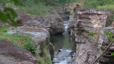 Calm-river-flowing-through-the-rocky-Cajones-de-Chame-canyon-in-Panama,-surrounded-by-lush-greenery