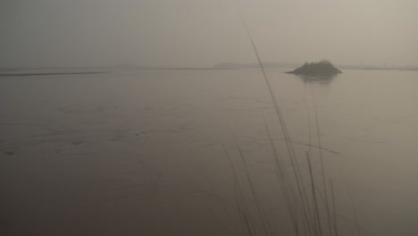 Dämmerungsdunst-über-Dem-Fluss-Ghanab,-Entfernte-Inselsilhouette,-Ruhiges-Wasser,-Gujarat,-Pakistan,-Heiter
