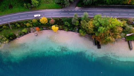 Un-Camino-Sinuoso-Atraviesa-Un-Frondoso-Bosque-Junto-A-Un-Resplandeciente-Lago-Azul