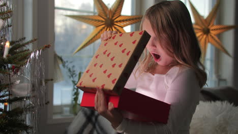 Magical-moment-of-little-girl-surprised-opens-Christmas-gift-lighting-her-face