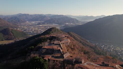 Panorama-Drohnenlandschaft-Der-Burgruinen-Von-Takeda,-Stadt-Hyogo-Asago,-Japan,-Himmel-Mit-Sonnenaufgangslicht-Und-Berggipfeln