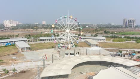 Rajkot-Atal-lake-drone-view-drone-camera-is-moving-towards-the-front-where-people-are-working-on-the-big-giant-wheel,-Rajkot-New-Race-Course,-Atal-Sarovar
