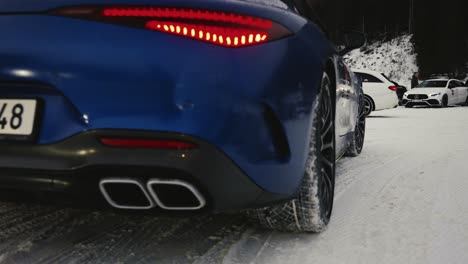 Un-Coche-Azul-Oscuro-Con-Llantas-Negras-Conduce-Por-Una-Carretera-Nevada-Durante-Un-Evento-De-Deriva-Invernal