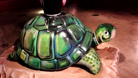 Funny-visitor-trying-to-drink-a-black-beer-situated-over-a-turttle-statue-at-Guinness-Storehouse