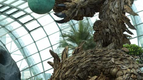 Wooden-dragon-sculpture,-the-centrepiece-of-Flower-Dome-glass-greenhouse-conservatory-at-Gardens-by-the-bay-during-festive-season,-to-celebrate-Lunar-new-year,-tilt-down-shot-of-the-dragon