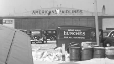 Vintage-American-Airlines-Hangar-with-Vehicles-and-Snow-Covered-Ground-in-1930s