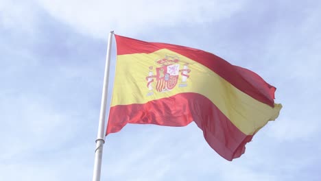 Spanische-Flagge-Weht-Im-Wind-In-Zeitlupe-Mit-Blauem-Himmel-Und-Wolken-Im-Hintergrund,-Aufnahme-Der-Spanischen-Flagge