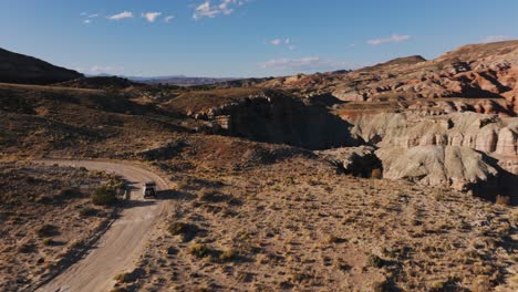 Car-Driving-Through-The-Desert-In-Bentonite-Hills-In-Utah,-USA---Aerial-Drone-Shot