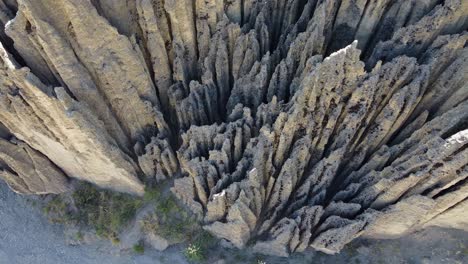 Aerial-looks-down-on-steep-eroded-conglomerate-rock-spires-in-nature