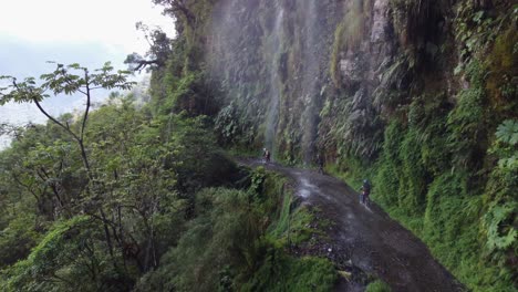 Luftaufnahme-Durch-Einen-Wasserfall,-Der-Radfahrern-Auf-Boliviens-Yungas-Rd-Folgt