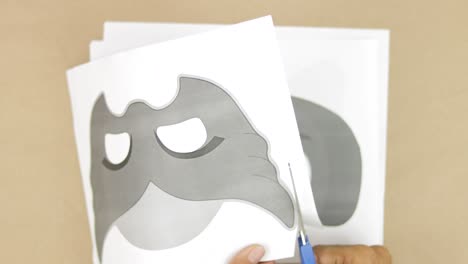Hands-cutting-out-printed-images-of-childrenss-masks-for-carnival,-making-molds