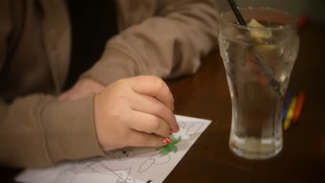 Child-coloring-a-picture-in-a-cafe-restaurant-sitting-at-a-table-with-colored-crayons