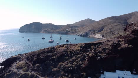 Antena-Reveladora-De-La-Bahía-De-La-Playa-Roja-Llena-De-Catamaranes,-Kokkini-Paralia,-Santorini,-Grecia