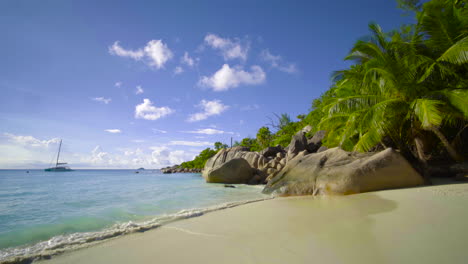 A-tranquil-sight-as-turquoise-waters-lap-against-the-shores-of-Mahe-Island-beach-in-Seychelles,-where-a-motionless-boat-rests