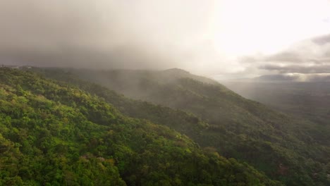 Mystic-drone-flight-over-lush-mountains-with-dense-grey-clouds-at-sky