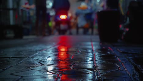 Scooter-red-backlight-reflection-on-wet-street-in-a-night-market-in-Bangkok