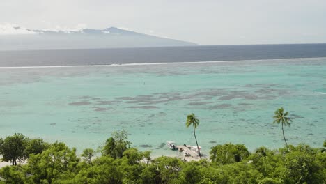 Filmische-Aufnahme-Eines-Bootsstegs-Eines-Privaten-Resorts-Auf-Der-Insel-Moorea-Mit-Tahiti-Im-Hintergrund