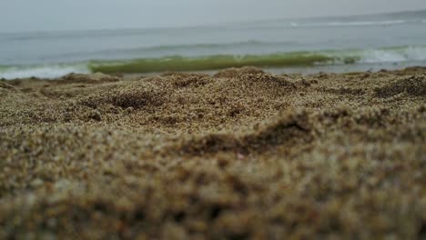 Nahaufnahme-Des-Sandes-Am-Strand-Mit-Verschwommenen-Meereswellen-Im-Hintergrund