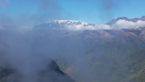 Aerial-crane-shot:-Snowy-capped-mountains-and-green-valleys-into-cloud