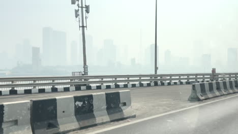 Eine-Limousine-Fährt-Auf-Mumbais-Bandra-Worli-Seeverbindung,-Im-Hintergrund-Sind-Die-Wolkenkratzer-In-Smog-Gehüllt
